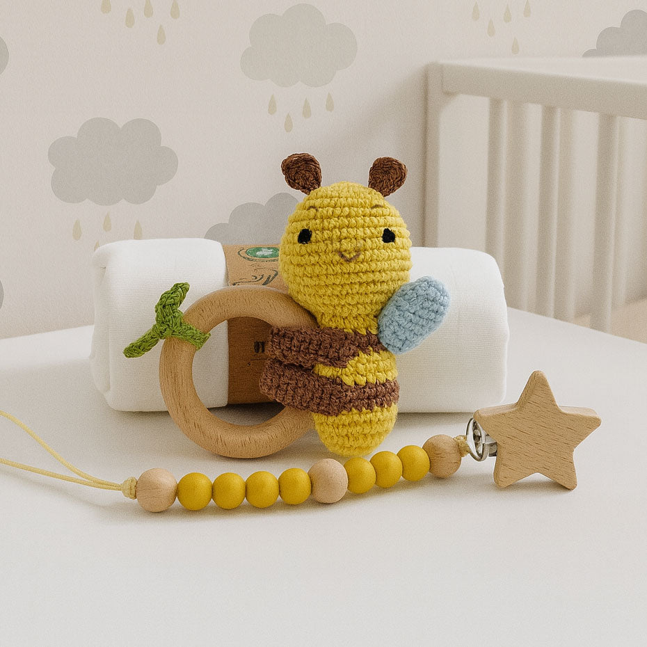 Crocheted bee toy with wooden ring and beaded chain on a crib