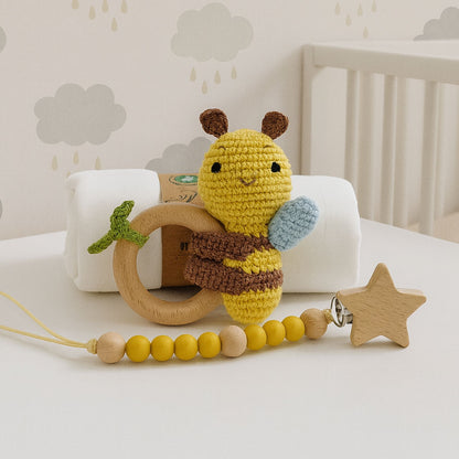 Crocheted bee toy with wooden ring and beaded chain on a crib