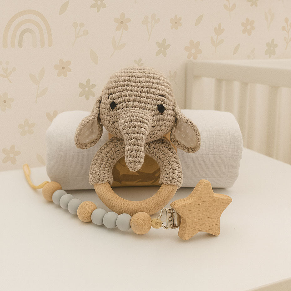 Crocheted elephant toy with wooden star rattle on a crib