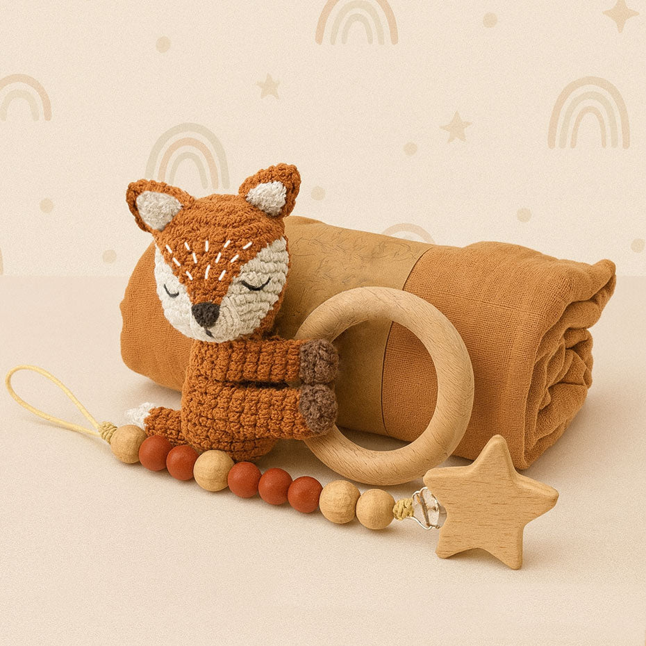 Baby comfort item set with fox plush toy, wooden ring, and star-shaped teether on a beige background.