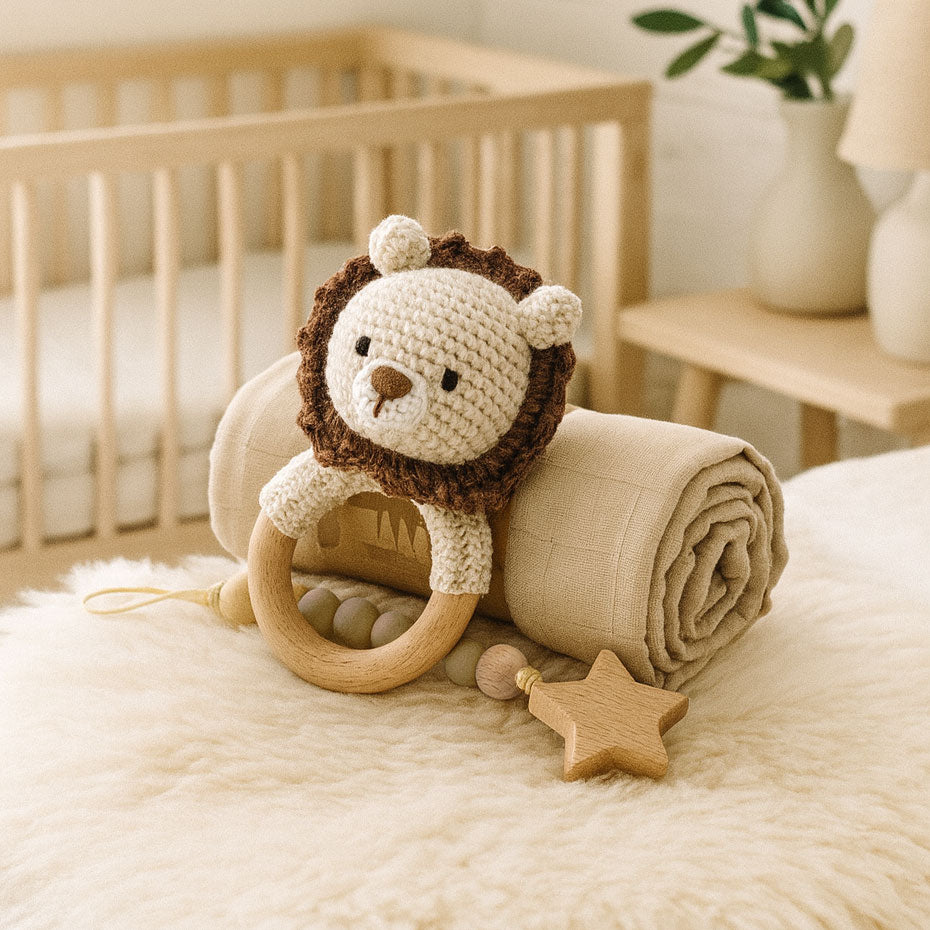 Crocheted lion toy with wooden ring and star on a blanket in a crib setting