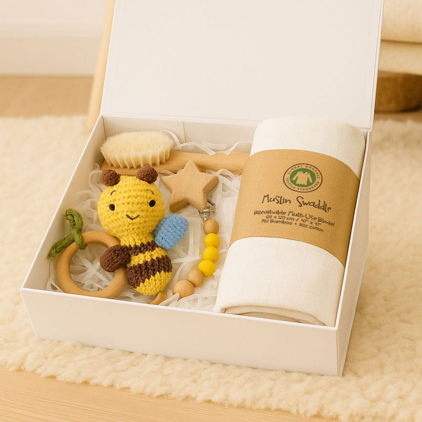 Gift set with a bee-themed teething toy, star-shaped item, and cylindrical product in a white box.