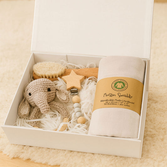 Baby care product set with elephant rattle, swaddle, and other items in a box.